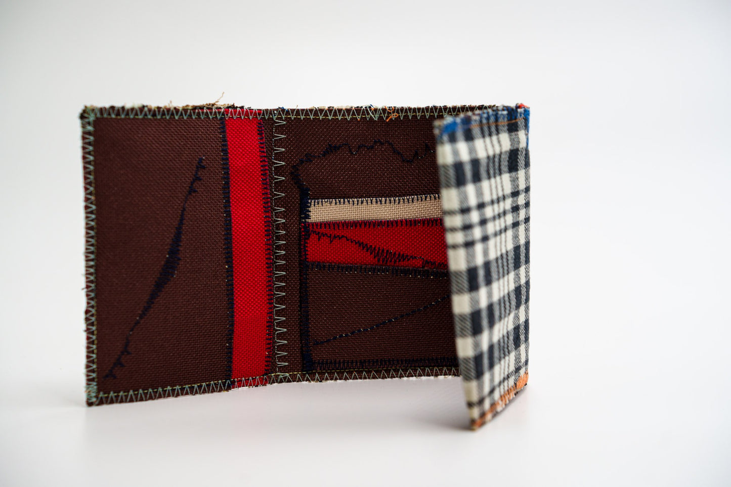 Wallet standing open, plaid exterior curving into the colorful red and brown interior