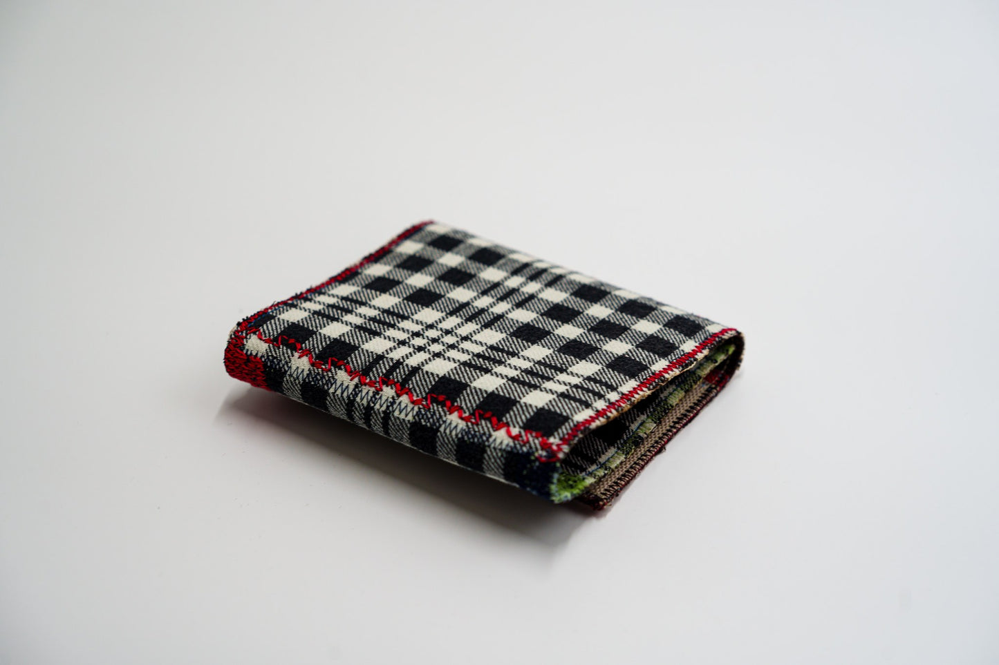 Black and pale-olive plaid wallet closed at an angle, handmade from an upcycled flannel shirt — HighSew