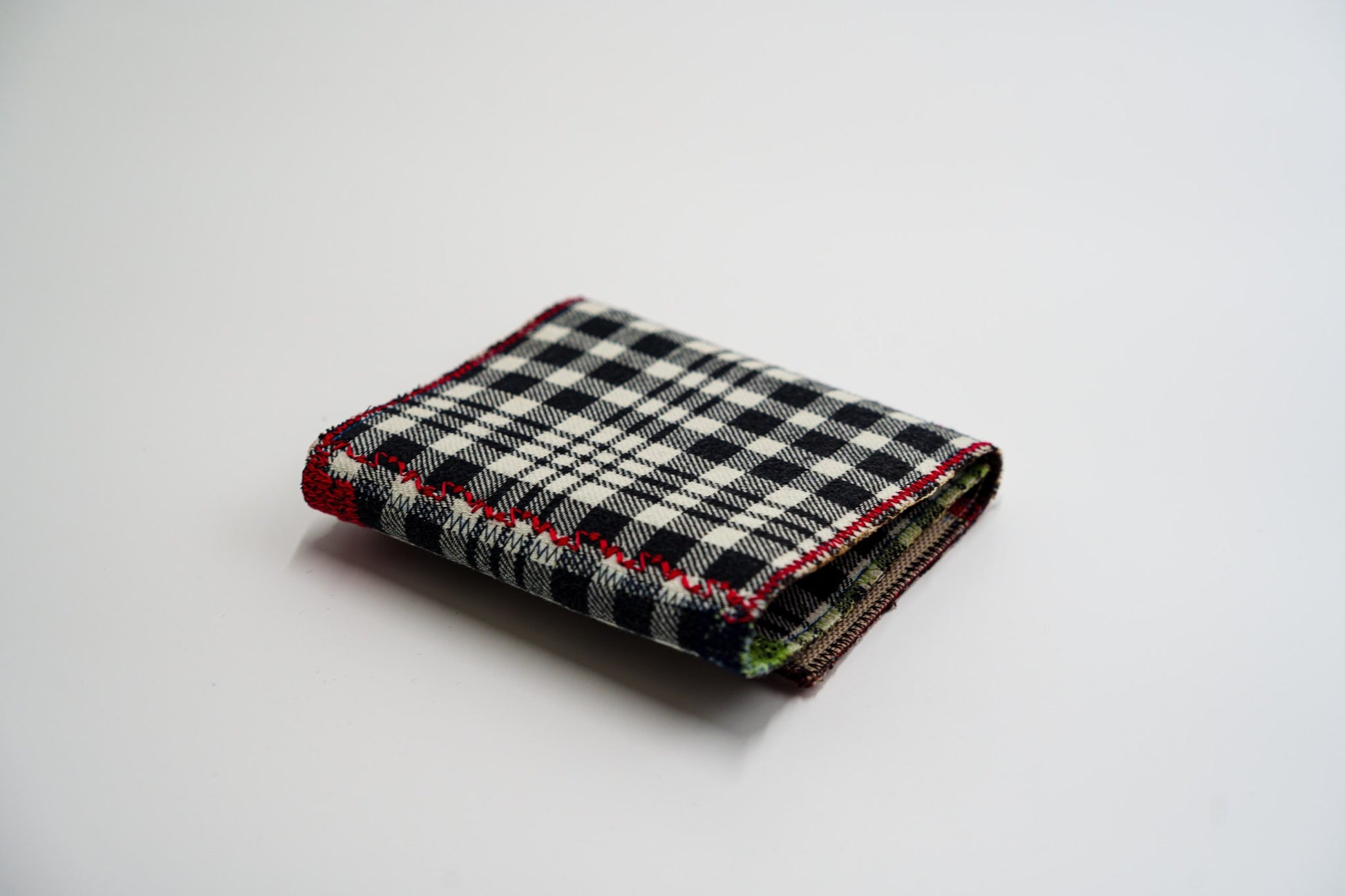 Black and pale-olive plaid wallet closed at an angle, handmade from an upcycled flannel shirt — HighSew