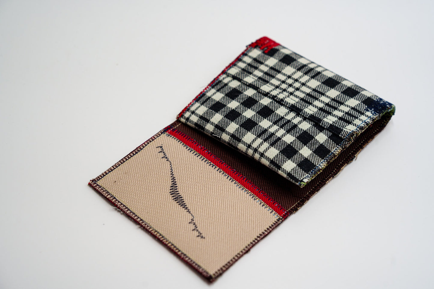 One-of-a-kind wallet half-open, colorful interior meeting black and pale-olive plaid — HighSew