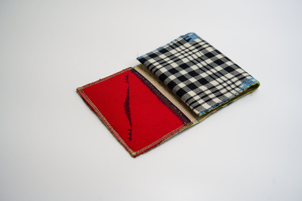 Upcycled flannel wallet half-open, black and pale-olive plaid meeting red interior — HighSew