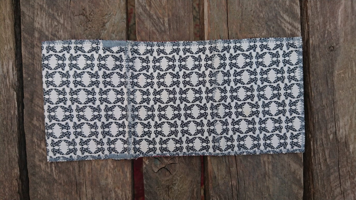 A one-of-a-kind wallet called "Butterflies Holding Hands" is made by Highsew. It is made of recycled shirt fabric combined with new, strong fabric. Outside view.