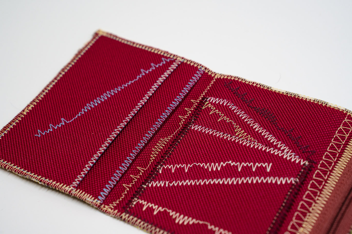 Close-up of colored signature stitching on deep red fabric — HighSew