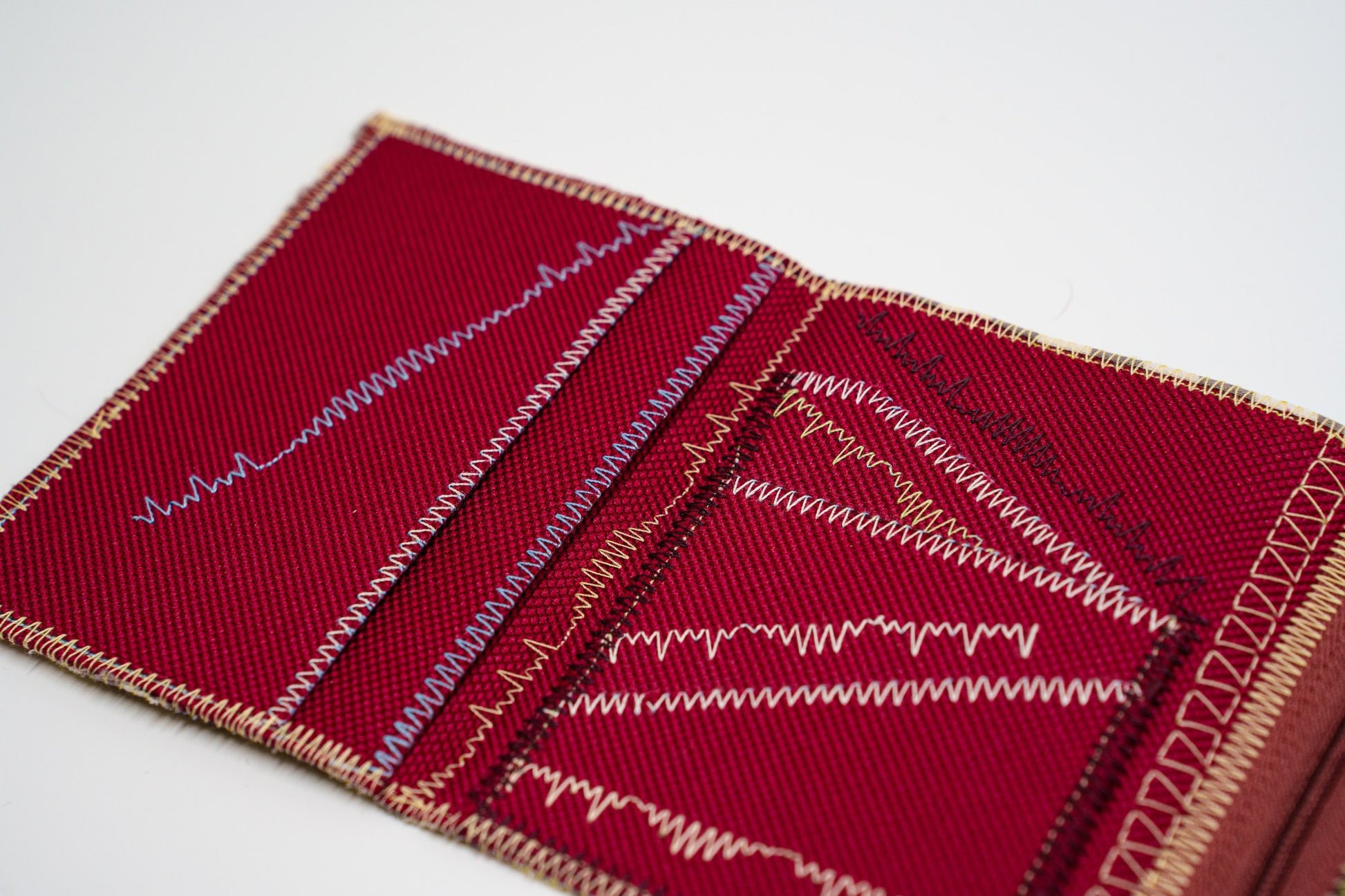 Close-up of colored signature stitching on deep red fabric — HighSew