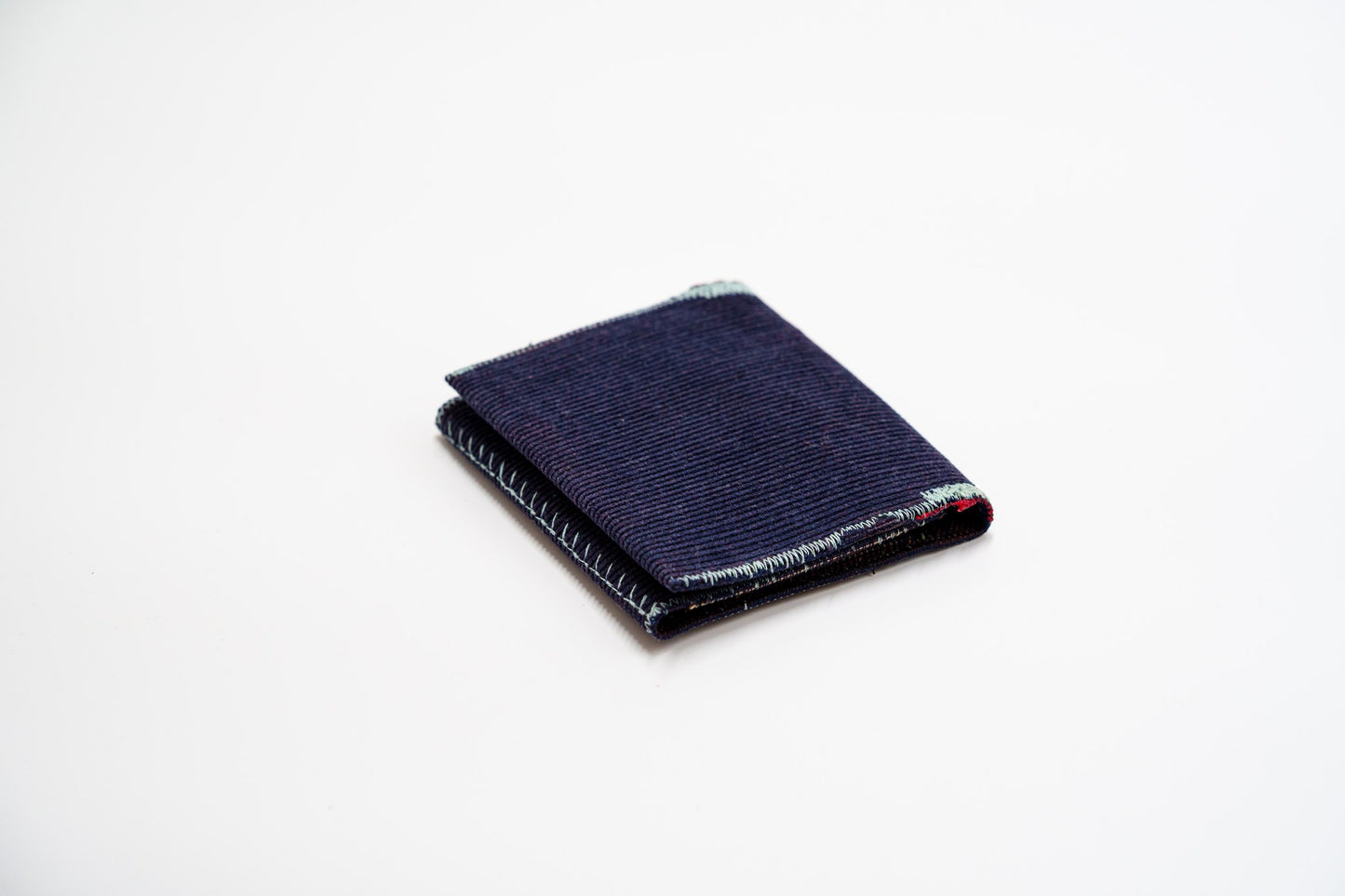 Deep blue corduroy wallet, closed at an angle, handmade from upcycled trousers — HighSew
