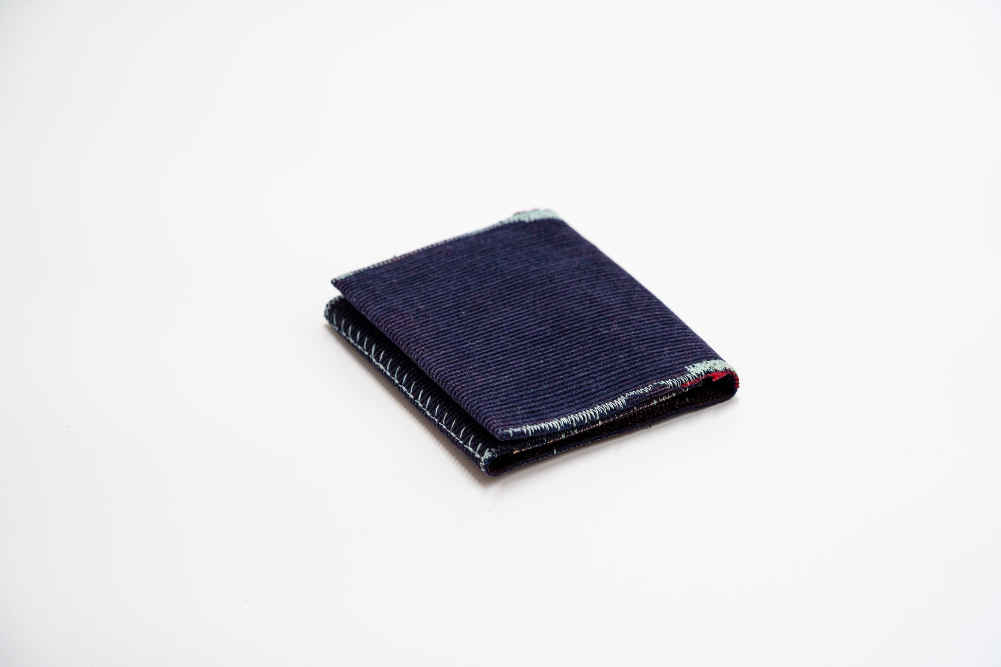 Deep blue corduroy wallet, closed at an angle, handmade from upcycled trousers — HighSew
