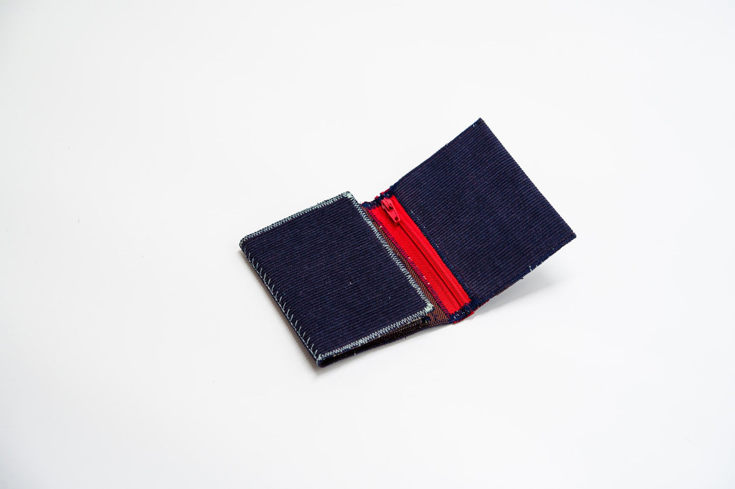 Blue corduroy wallet half-open, red zip meeting the deep blue exterior — HighSew