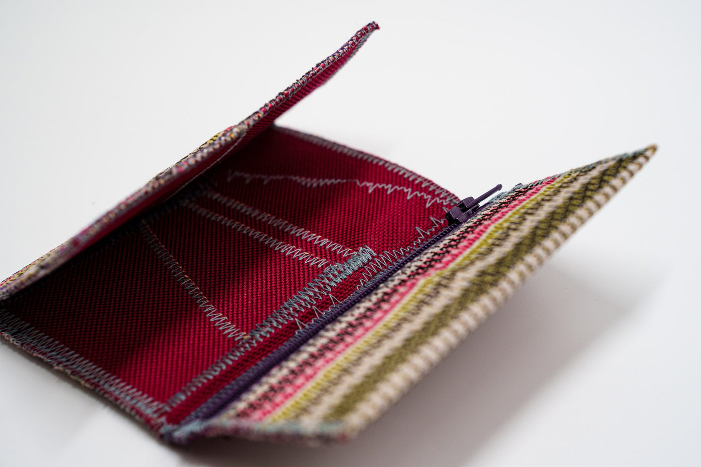 Upcycled woven wallet open at an angle, red interior — HighSew