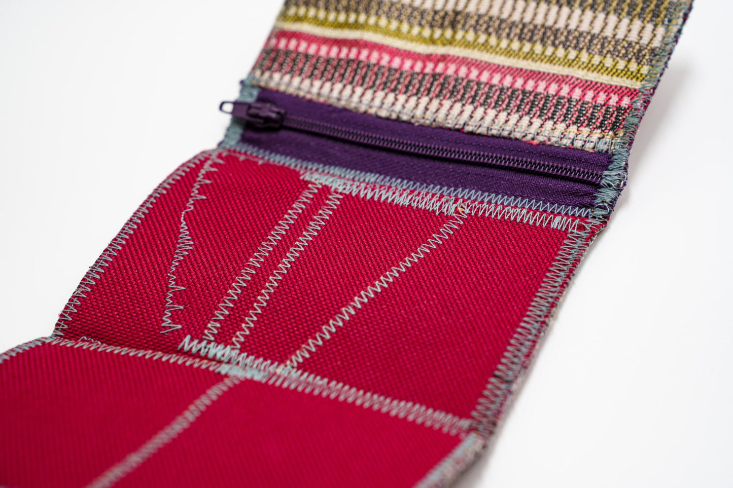 Close-up of zigzag signature stitching and purple zip on red fabric — HighSew