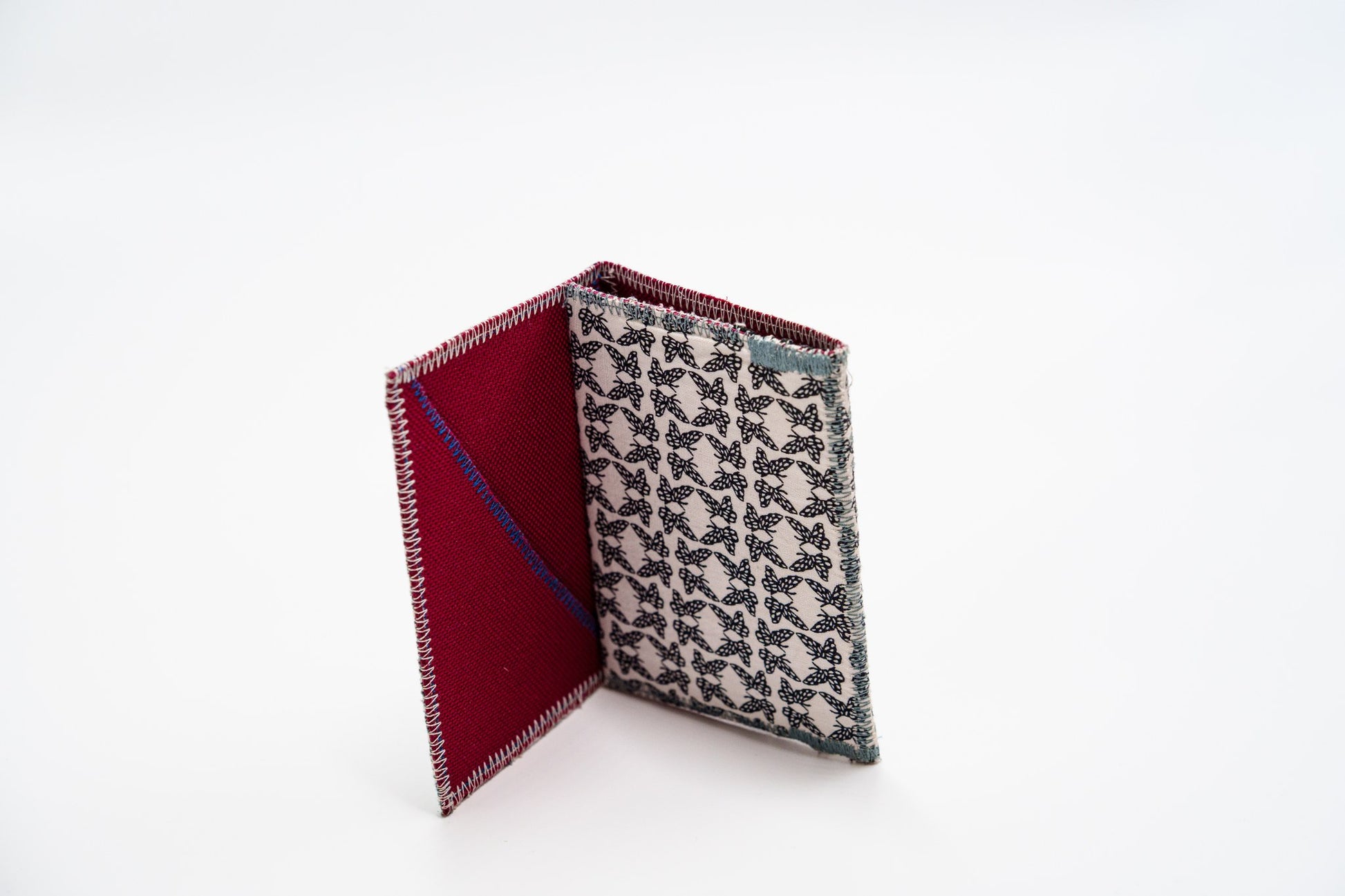 Upcycled butterfly-print wallet standing open, red interior — HighSew
