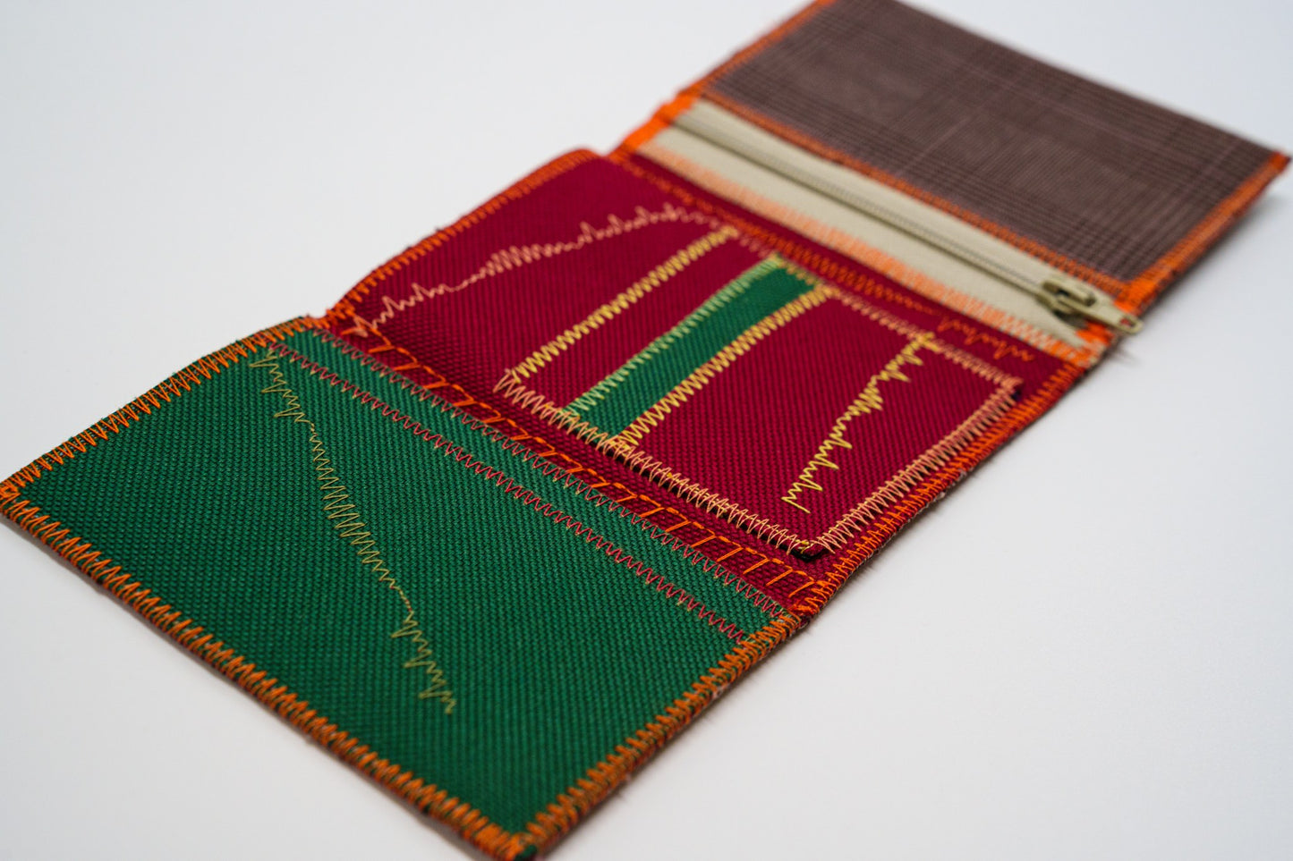 Upcycled wallet open at an angle showing green and red interior — HighSew