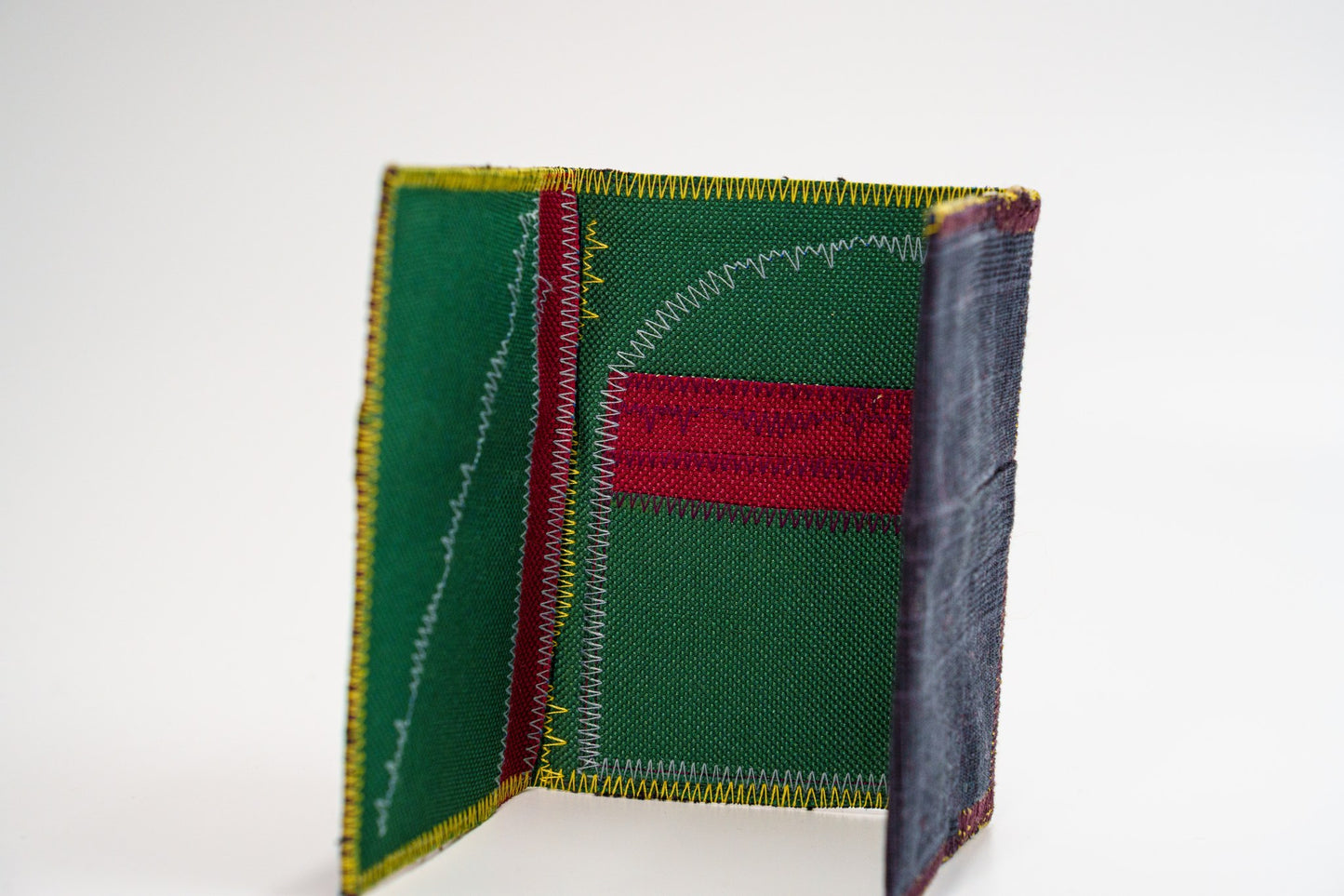 Upcycled green-interior wallet standing open, dark plaid exterior — HighSew