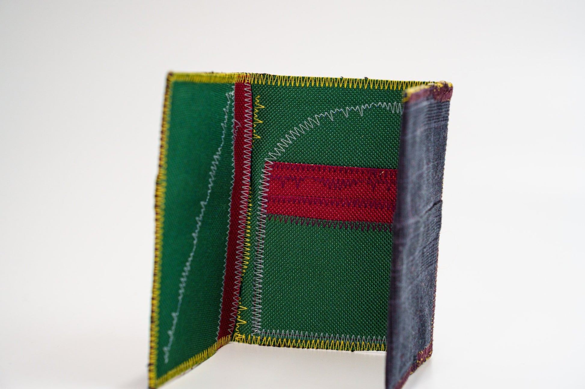Upcycled green-interior wallet standing open, dark plaid exterior — HighSew