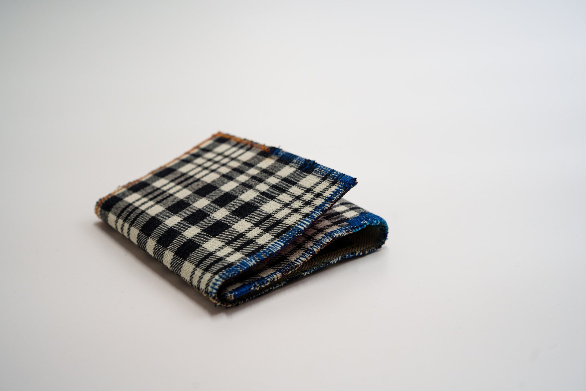 Black and pale-green plaid wallet closed at an angle, handmade from an upcycled flannel shirt — HighSew