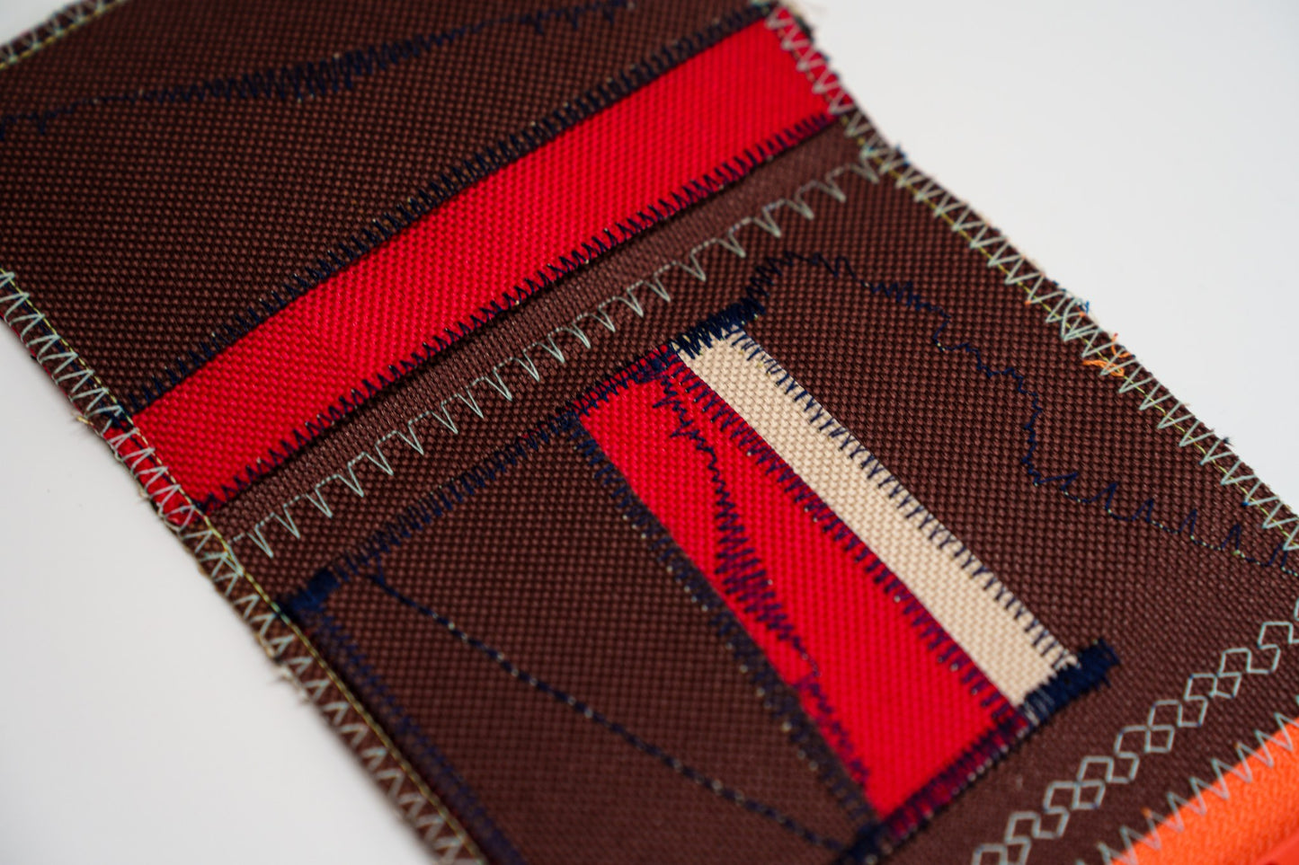Close-up of the wallet interior — red and brown panels with a sand-colored strip and navy zigzag stitching