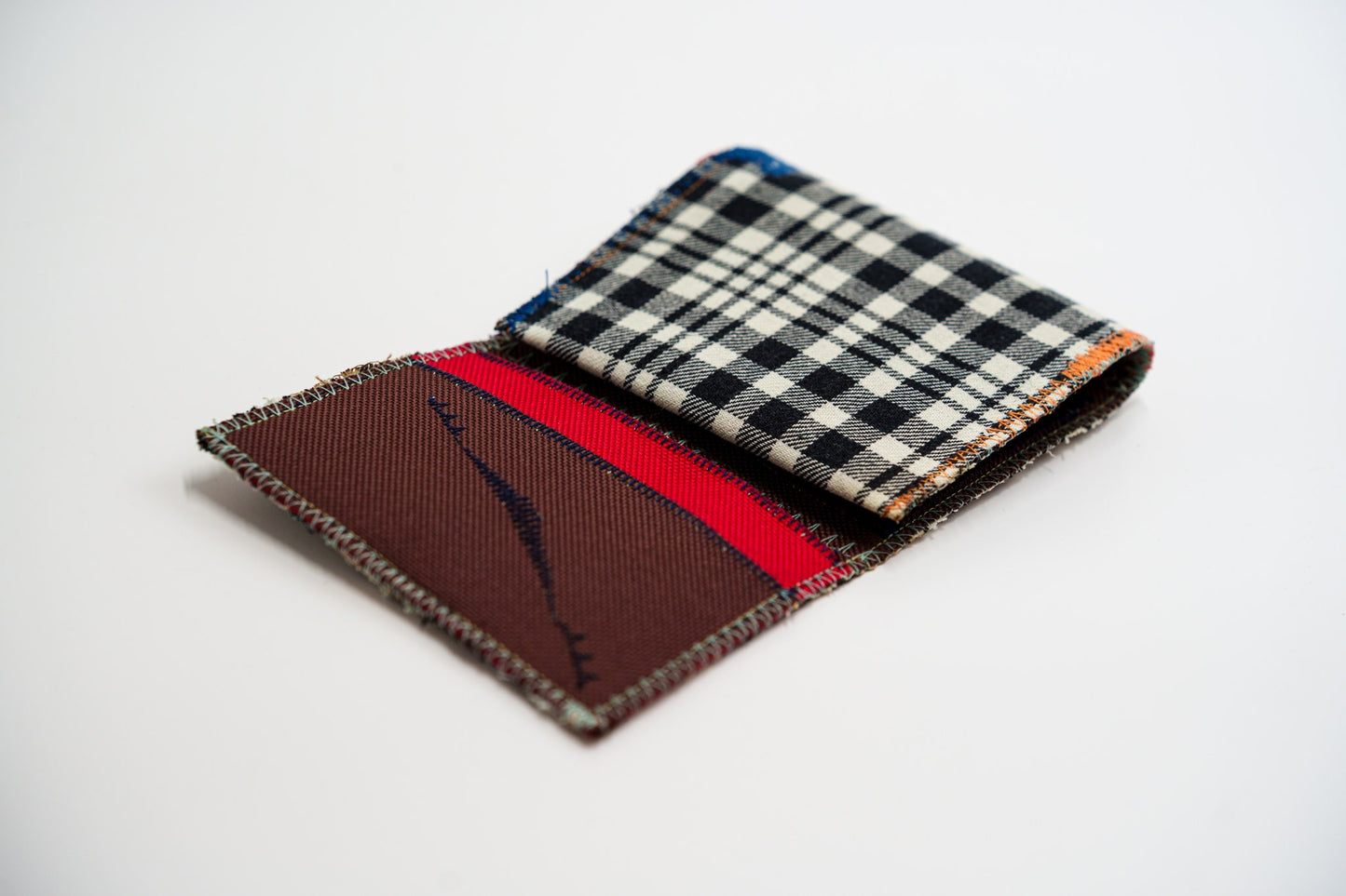 Half-open wallet, black and pale-olive plaid exterior meeting the red and brown interior