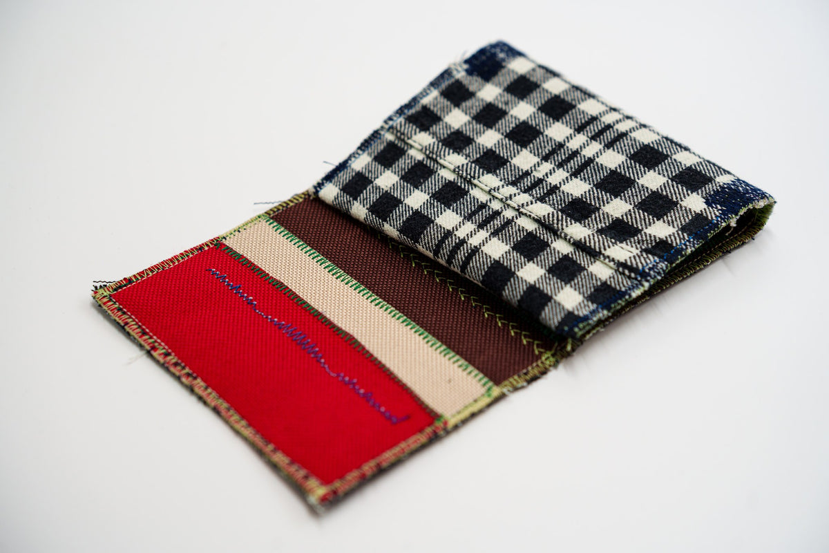 One-of-a-kind wallet half-open, colorful interior meeting black and pale-olive plaid — HighSew
