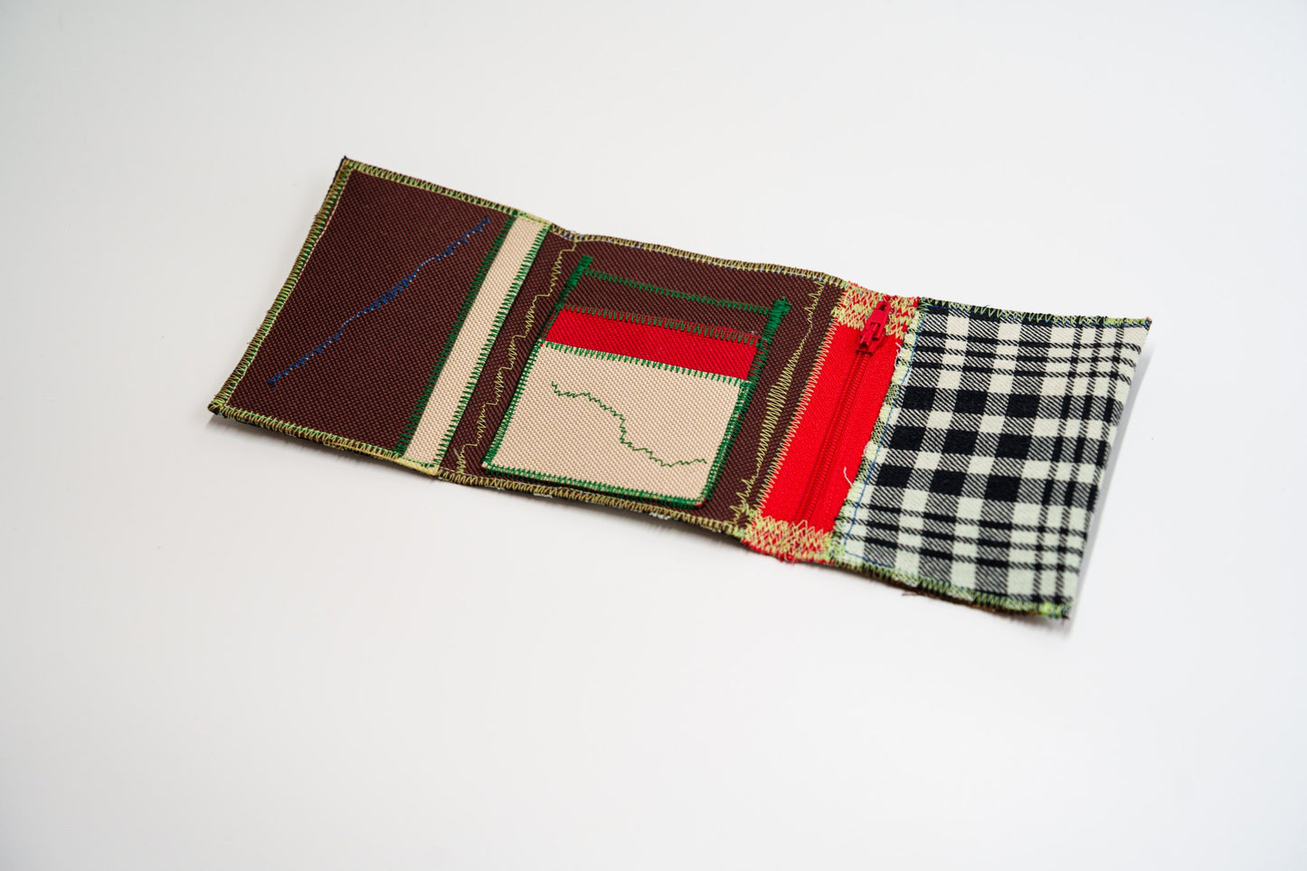 Wallet open flat, top-down: deep brown interior with a red panel, sand card slot and a red zip
