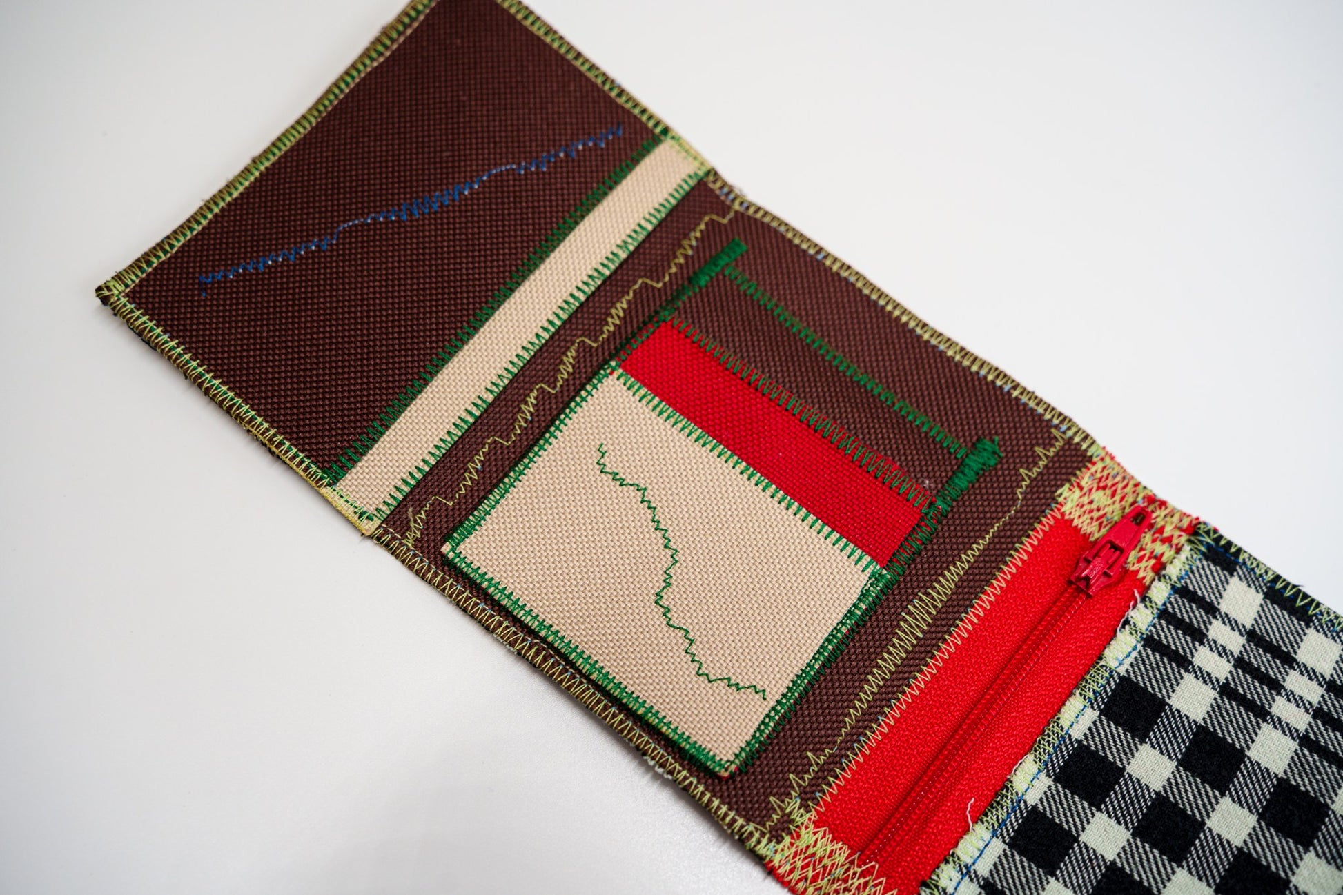 Close-up of the wallet interior — brown and red panels with a sand-colored card slot and colored zigzag stitching